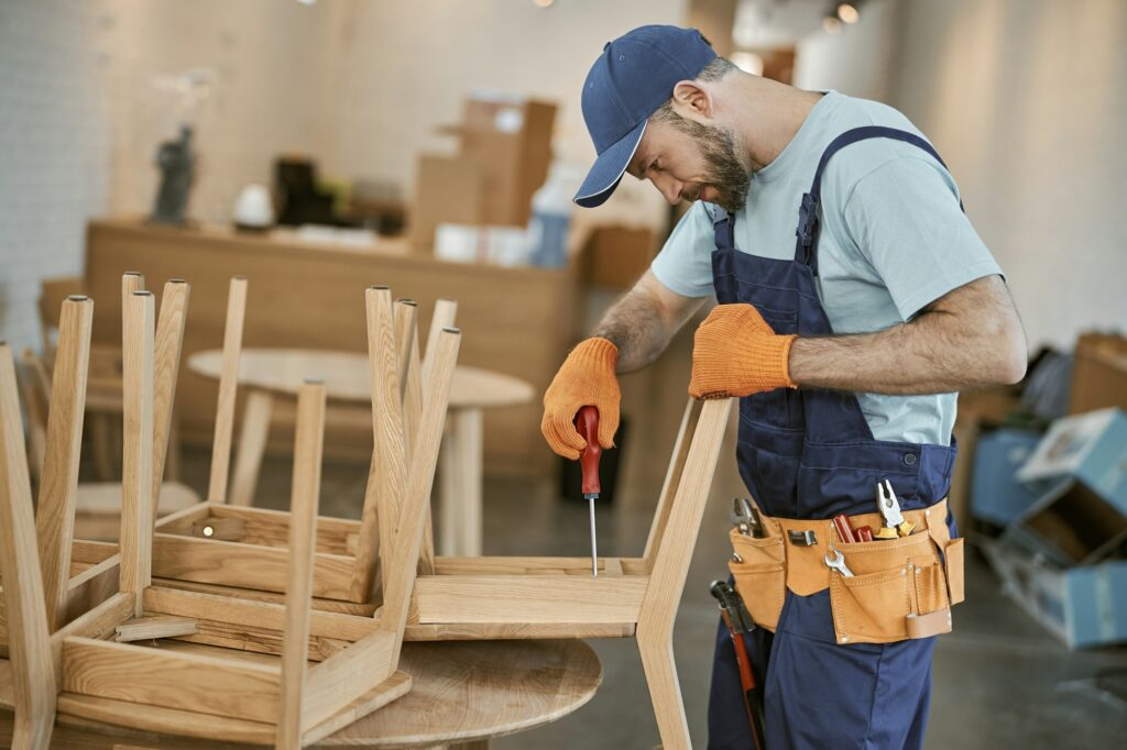 Bearded young man repairing chair in cafe